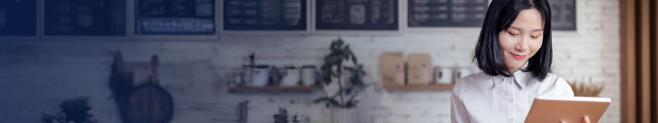 Woman holding tablet behind a service counter.