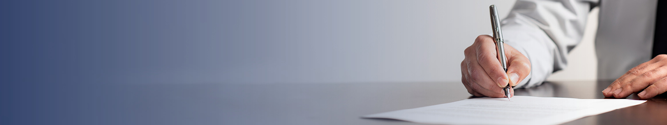 Person signing paper on desk.