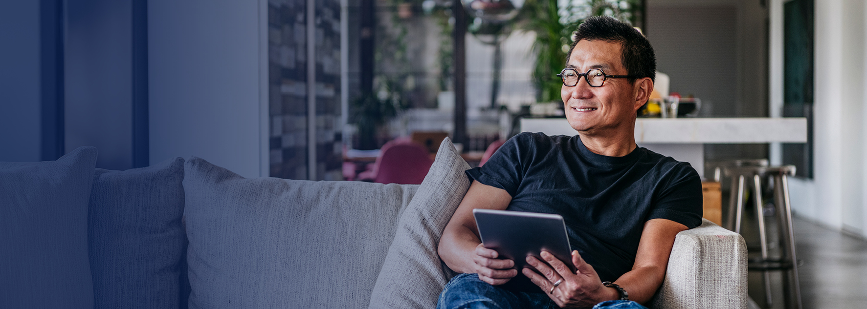 Man sitting on couch in living room looking at a tablet