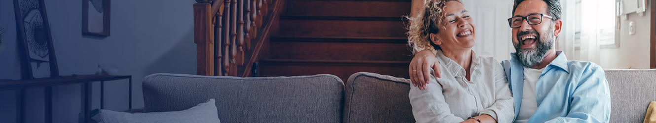 Two people sitting on couch and laughing.