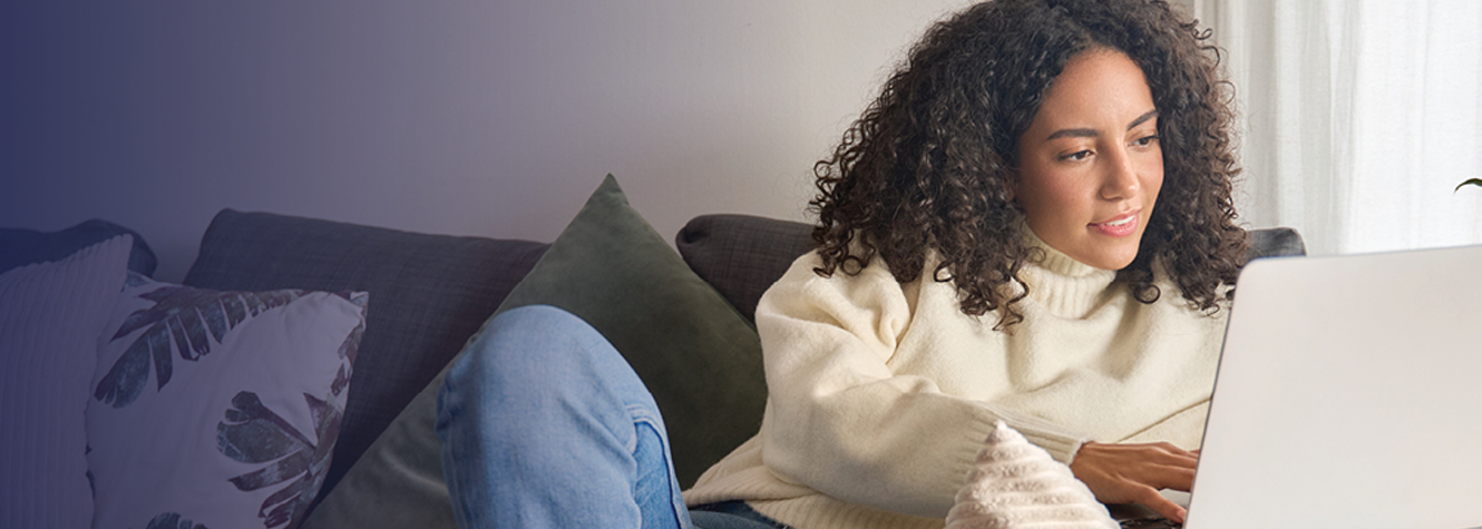 Woman sitting on her couch using her laptop.