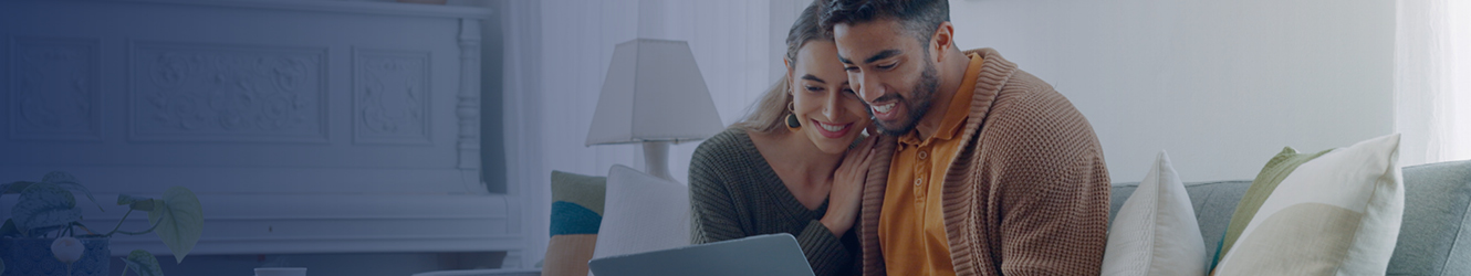 Couple sitting on couch, looking at their computer.