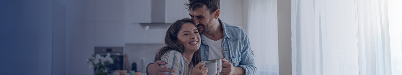 Couple smiling, enjoying coffee in their new kitchen.